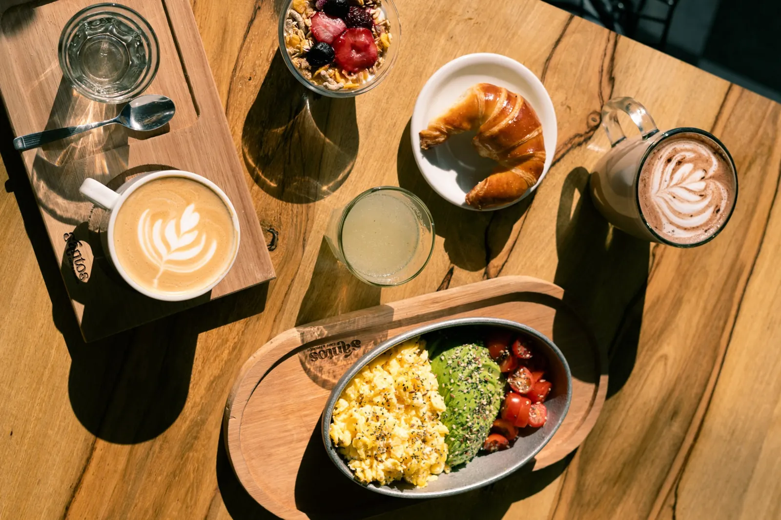 Mesa larga con cafés con leche, limonadas y espresso tonic al atardecer en Santos Café & Brunch
